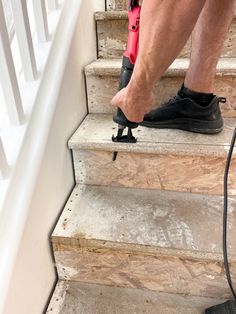 a man in black shoes is on the stairs with a red and black cordless drill