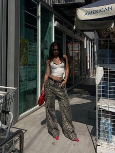 a woman standing on the sidewalk in front of an american apparel store wearing leopard print pants