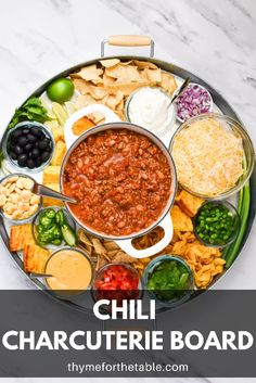 a platter filled with chili, cheese and tortilla chips on top of a marble table