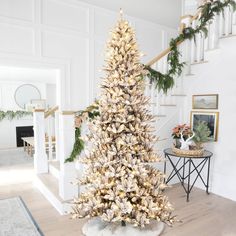 a decorated christmas tree in the middle of a living room with stairs leading up to it