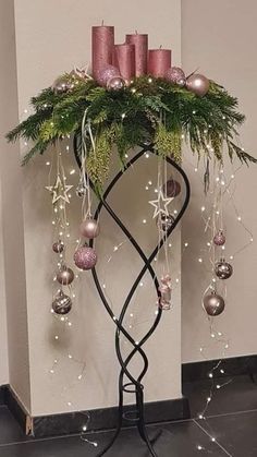 a christmas tree with candles and ornaments on it's stand in front of a wall