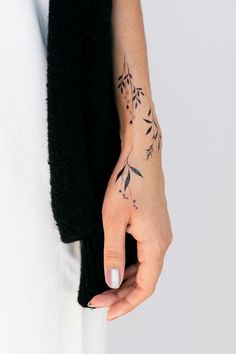 a woman's hand with a small tattoo on her left wrist and the other arm