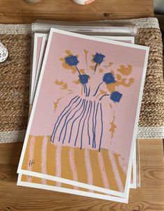 three cards with blue and yellow flowers in a vase on top of a wooden table