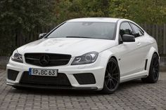 a white mercedes c - class parked in front of a fence