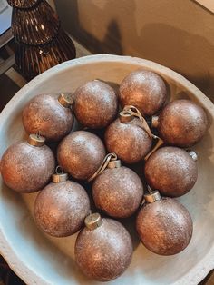 a white bowl filled with brown ornaments on top of a table