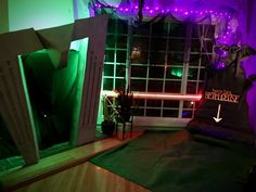 a room decorated for halloween with purple and green lights