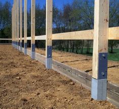 the fence is made of metal and wood, along with some dirt on the ground