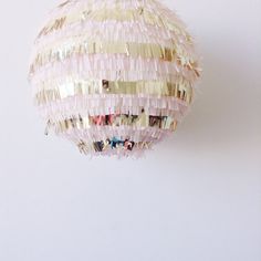 a pink and white ball hanging from the ceiling with fringes on it's sides