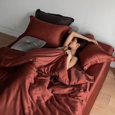 a woman laying in bed with red sheets