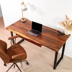 a laptop computer sitting on top of a wooden desk next to a brown leather chair