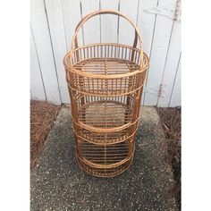 a brown rattan basket sitting on top of a cement floor next to a white wall