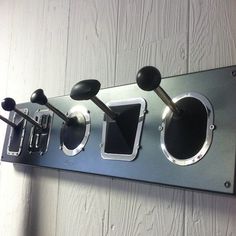 a metal wall mounted device with three knobs and two spoons on the side