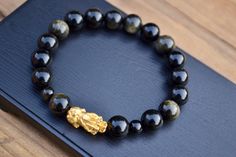 "This is Pure Real 24 Karat Solid Gold Pixiu/Black Obsidian Beads Solid Gold Pixiu / Piyao - Approximately 18-19mm x 10mm Black Obsidian - Approximately 10mm/Approximately 6mm Please select bracelet size. All are handmade with care .Strung on heavy duty stretchy/elastic. Products and photo may differ. Bracelet Comes with Storage Bag & Box How to Determine Bracelet Size: Step 1: Measure your wrist just below the wrist bone, where one would normally wear a bracelet, with a flexible measuring t Gold Spiritual Obsidian Jewelry, Elegant Obsidian Bracelets For Meditation, Gold Obsidian Jewelry As A Gift, Elegant Hand-strung Obsidian Jewelry, Elegant Hand-strung Bracelets For Good Luck, Obsidian Dragon, Pixiu Bracelet, Dragon Bracelet, Lucky Bracelet