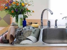 a kitchen sink filled with dirty dishes and utensils next to a vase of flowers