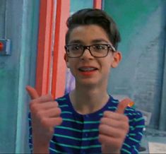 a young boy wearing glasses giving the thumbs up