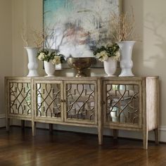 an ornate sideboard with vases and flowers on it in front of a window