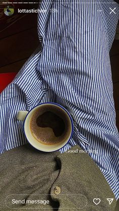 a cup of coffee sitting on top of a person's lap next to a pillow