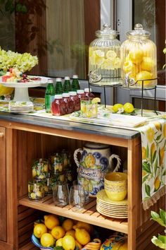 a wooden table topped with lots of lemons and cups next to a vase filled with flowers