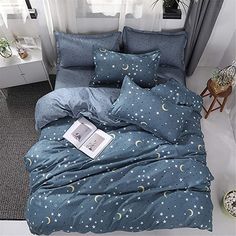 a bed with blue comforter and pillows on it in a room next to a window