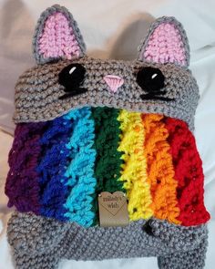 a crocheted stuffed animal is wearing a rainbow scarf