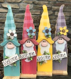 three gnomes sitting on top of wooden boards with welcome signs in front of them