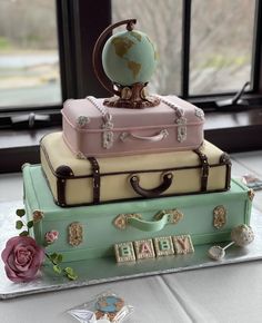 a cake made to look like suitcases with a globe on top and the words happy birthday written in small letters