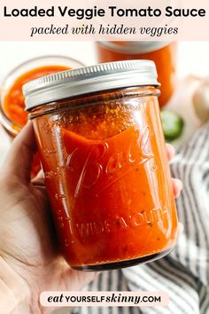 a hand holding a jar of loaded veggie tomato sauce with the title above it