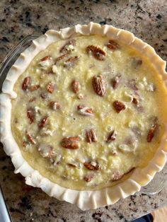 a pie sitting on top of a table next to a knife and bowl filled with nuts