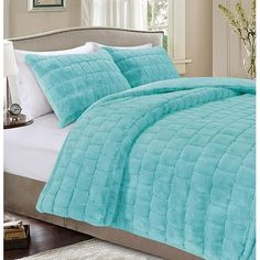 a bed with a blue comforter and pillows