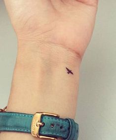 a woman's wrist with a small bird tattoo on the left side of her arm