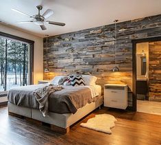 a bedroom with wood paneling and a bed in the middle, next to a large window