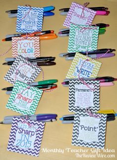 several colorful tags with writing on them sitting on a table next to markers and pens