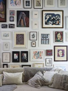 a living room filled with lots of framed pictures on the wall next to a couch