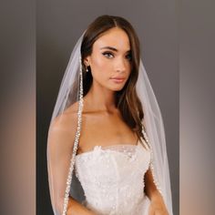 a woman wearing a wedding veil with pearls on it