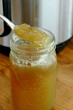 a jar filled with liquid sitting on top of a wooden table next to an electric pressure cooker