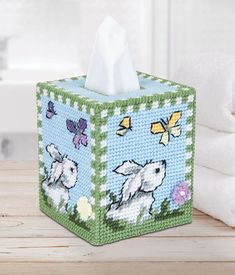 a tissue box with sheep and butterflies on it sitting on a table next to towels