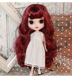 a doll with long red hair standing next to a dresser