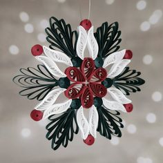 a paper snowflake ornament with red and white decorations hanging from it