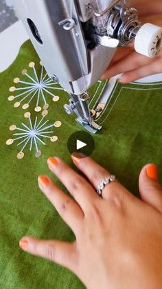 someone is using a sewing machine to sew something on the green tablecloth that they are sitting on