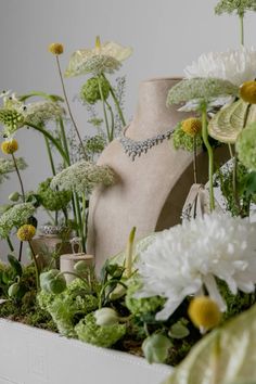 a vase filled with flowers next to a mannequin