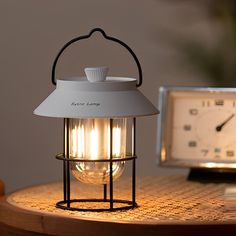 a lamp sitting on top of a wooden table next to a clock and an alarm