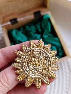 a gold brooch sitting in a wooden box