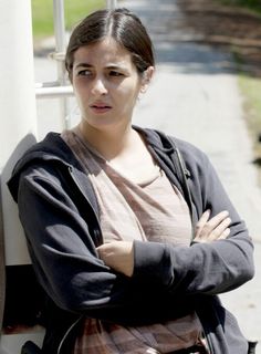 a woman with her arms crossed leaning against a wall