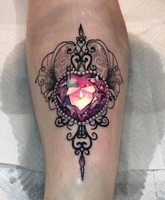 a woman's leg with a tattoo on it and a pink diamond in the center