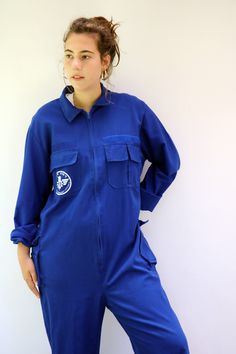 "Vintage blue chore coveralls from Israeli flight school printed in Hebrew on the back and front...\" Amal Ramat David Building the future\" with an F16 airplane drawing on the back panel, pockets with velcro opening, zips down the front, elastic waist on the back, soft cotton. an oversize and loose fit can be worn by both men and women. aside from minor signs of wear...The back hem of the pants is worn, otherwise, good vintage condition clean ready to wear. **Model is 5'8\" and a size s/m for r Mustard Jumpsuit, Hippie Shorts, Empire Waist Gown, Flight School, Airplane Drawing, Workwear Overalls, Vintage Jumpsuit, Blue Jumpsuit, Vintage Silk Scarf