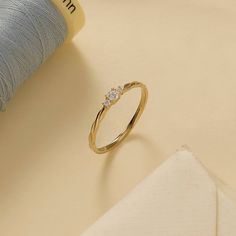 a gold ring sitting on top of a table next to a ball of thread and spool of yarn