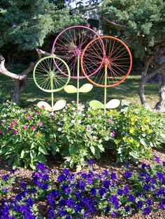 three metal garden art pieces sitting in the middle of flowers