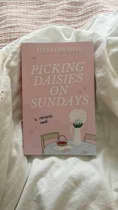 the book picking daisies on sunday's is sitting on a bed with white sheets