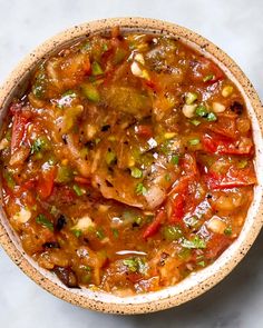 a bowl filled with meat and vegetables on top of a white countertop next to a spoon