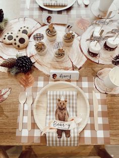 a wooden table topped with plates and cups filled with desserts covered in frosting